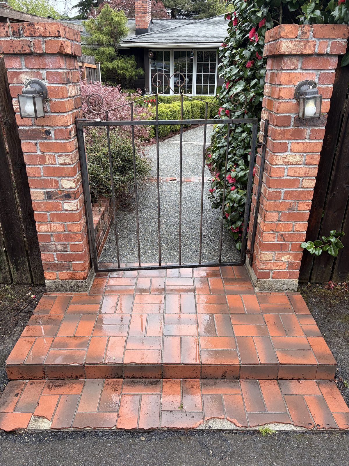 Same brick walkway and entry gate after pressure washing — vibrant, clean, and fully restored